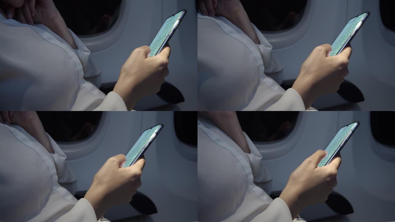 亚洲女性使用智能手机在晚上在飞机上寻找商业计划