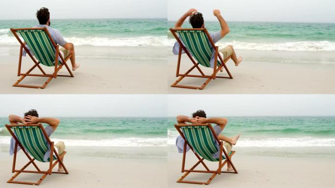 男子在4k海滩太阳椅上双手放在头顶放松的后视图