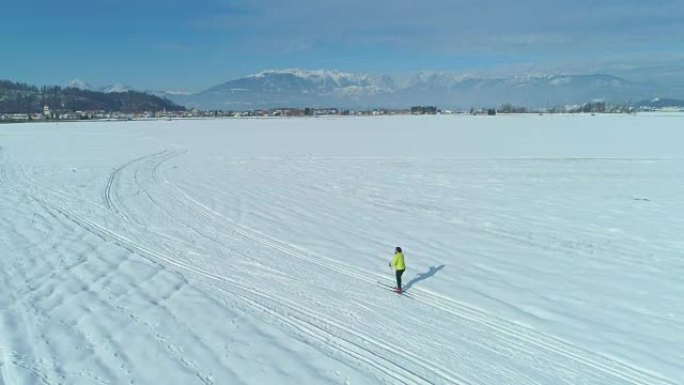 空中: 在白雪中沿着小径滑雪的活跃女性身后飞行。