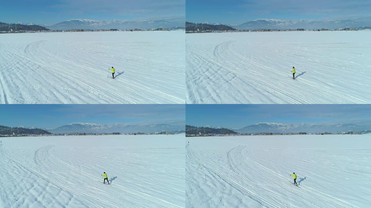空中: 在白雪中沿着小径滑雪的活跃女性身后飞行。