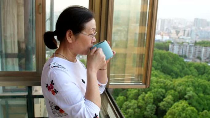 高级妇女喝茶，看着窗外