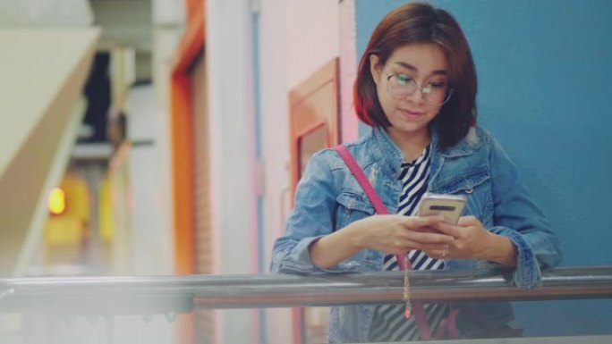 年轻的亚洲女性在城市夜晚使用智能手机。