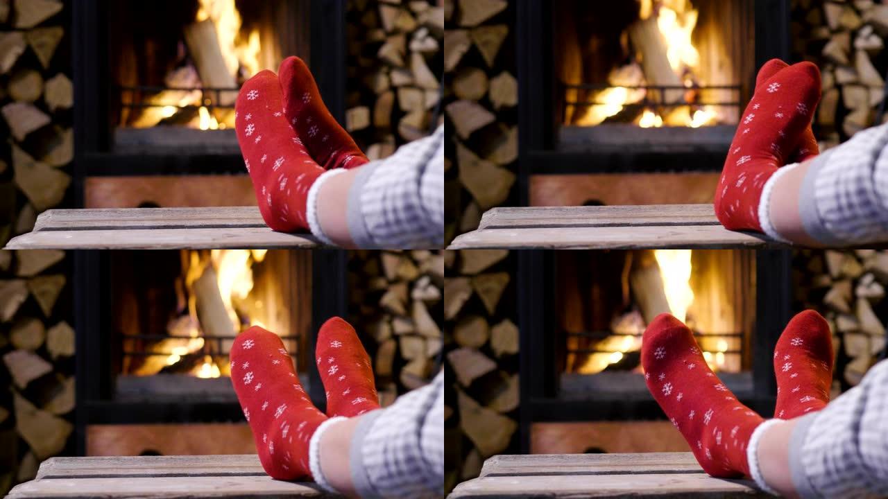 寒冷的秋天或冬天的晚上。人们用毯子和茶在炉火旁休息。穿着羊毛袜的脚的特写照片。舒适的场景。