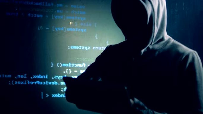 伪装的黑客正在用投影数据在墙旁边操作平板电脑