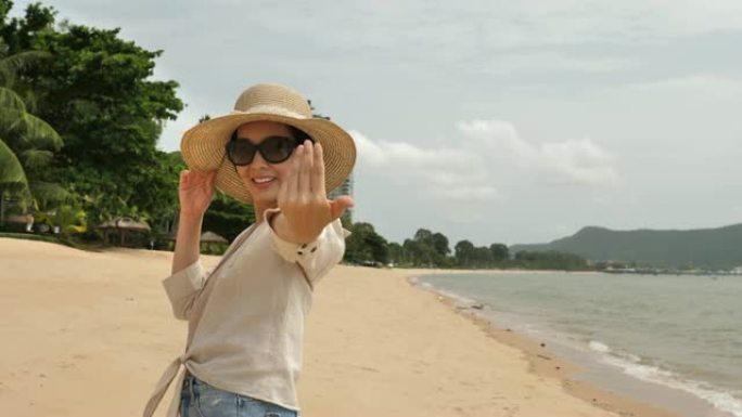 女人欢迎你和她一起在海滩散步。女游客享受暑假旅行展示欢迎手势微笑快乐