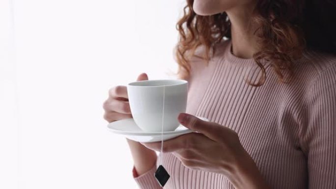 年轻微笑的女人拿着杯子喝茶，特写镜头