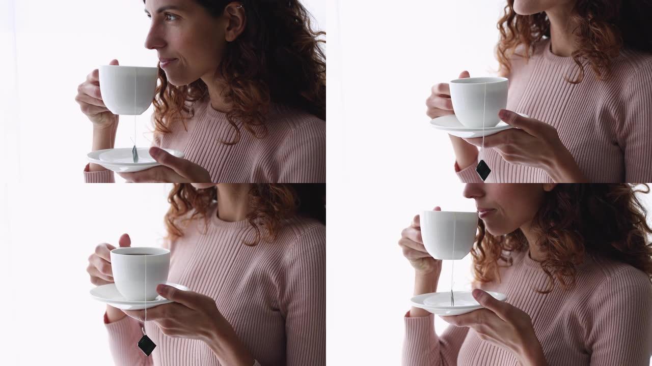 年轻微笑的女人拿着杯子喝茶，特写镜头