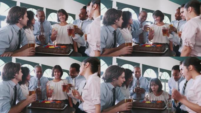 女商人在酒吧与同事一起庆祝生日蛋糕上吹蜡烛