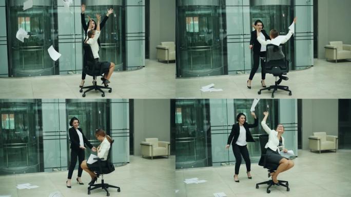 兴奋的女商人在滚动的椅子上旋转，向空中扔纸，笑着玩得开心。积极的情绪、工作和同事的概念。