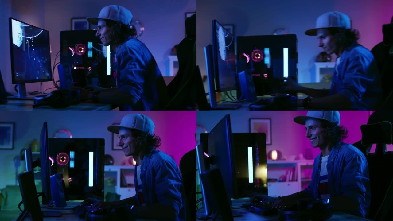 兴奋的玩家在他的个人电脑上玩并赢得第一人称射击游戏在线视频游戏。房间和电脑有彩色霓虹灯。年轻人戴着帽