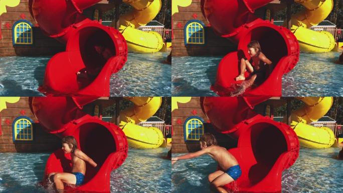 男孩在水上公园的红色水滑梯上滑行