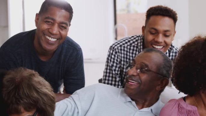 多代黑人家庭坐在一起放松，对着镜头微笑，特写镜头