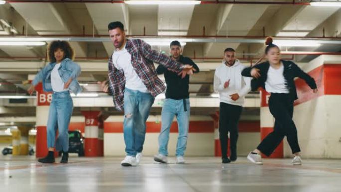 不同种族的年轻城市舞者的慢动作正在地下停车场进行训练