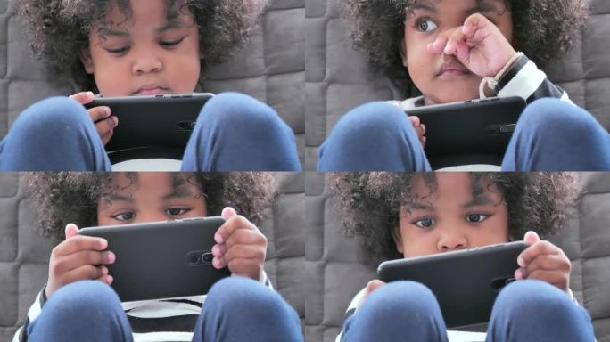 非洲种族的小男孩年龄2-3岁在家通过智能手机在家上学，以防止冠状病毒或Covid-19.Family