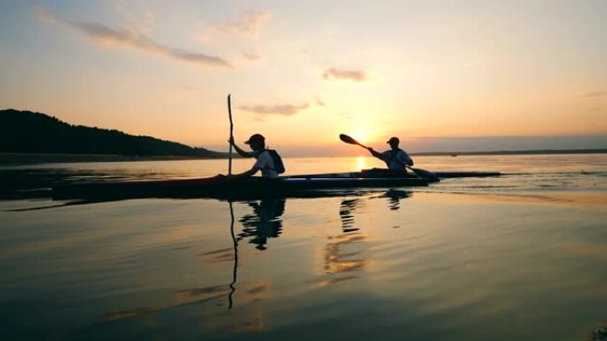 人们在日落时在湖上航行独木舟