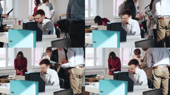 紧张而疲惫的年轻英俊的欧洲男性业务经理在繁忙的现代办公桌上使用笔记本电脑。