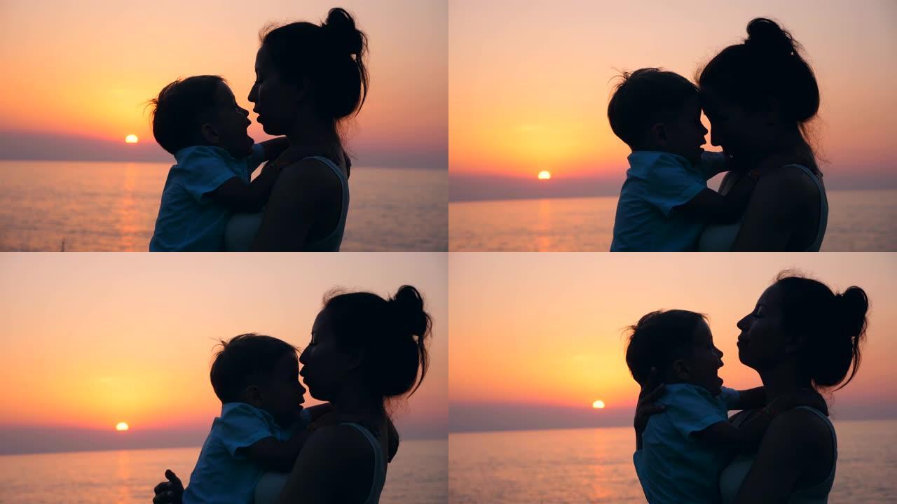 一个孩子和他的母亲在日落时拥抱和亲吻。母亲和婴儿，母性概念。