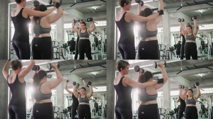 超重的女人和教练在健身馆用哑铃锻炼。
