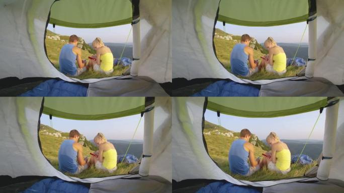 特写: 年轻夫妇坐在帐篷前给朋友发短信。