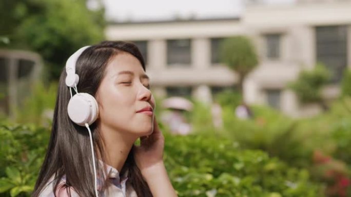 一位年轻女子正在公园里闭着眼睛欣赏音乐
