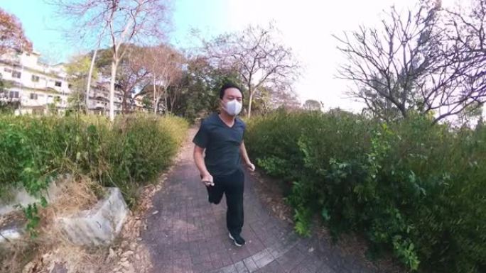 亚洲男子戴着空气污染面具在公园跑步