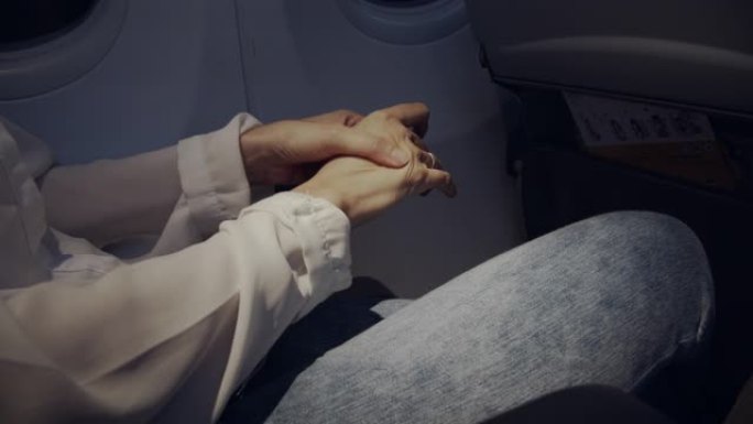 亚洲妇女在夜间飞行时在飞机上按摩她的手