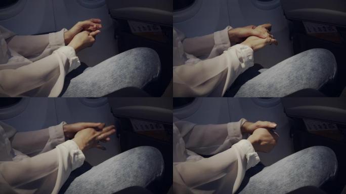 亚洲妇女在夜间飞行时在飞机上按摩她的手