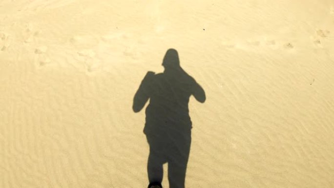 男人在海滩慢跑。移动阴影