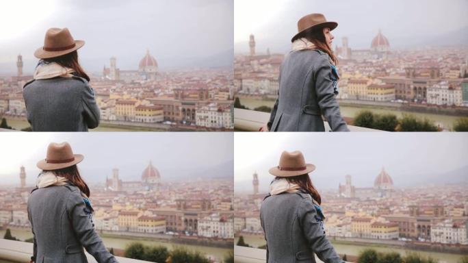 穿着暖和衣服的快乐微笑的旅游女孩在下雨天走上前欣赏意大利佛罗伦萨的美丽全景。