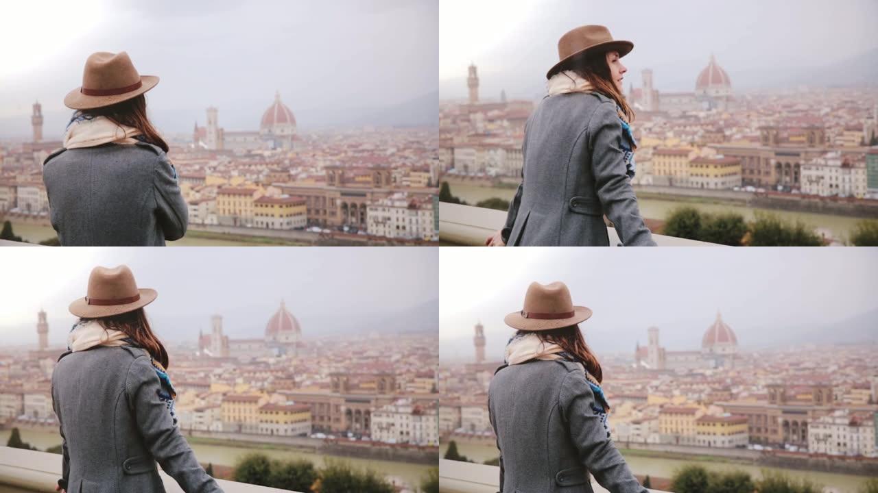 穿着暖和衣服的快乐微笑的旅游女孩在下雨天走上前欣赏意大利佛罗伦萨的美丽全景。