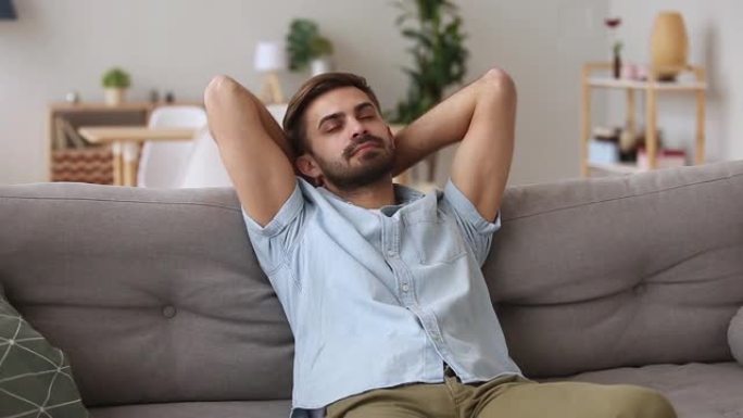 千禧一代的男人在沙发上休息，在家里度过了一个懒惰的周末