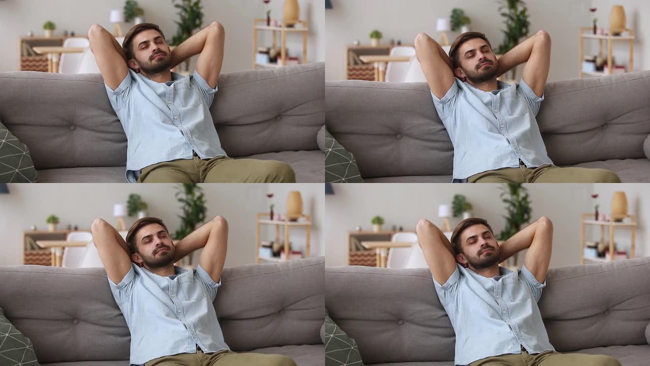 千禧一代的男人在沙发上休息，在家里度过了一个懒惰的周末