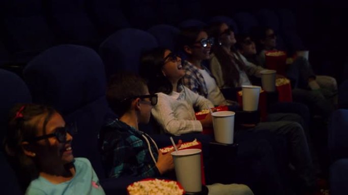 拉丁美洲的一群孩子在电影院里一边欣赏喜剧3D电影，一边享受小吃