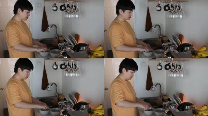 一位亚洲中国中年妇女喜欢早上在厨房准备早餐，一边听耳机