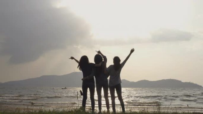 慢动作-年轻亚洲女孩的剪影组，在海上或湖边一起放松情绪。露营、旅行和友谊概念。