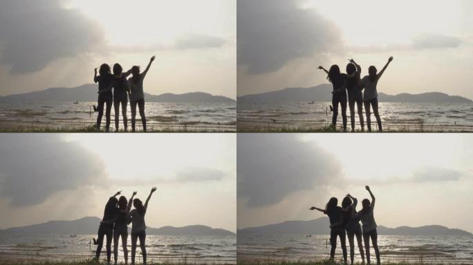 慢动作-年轻亚洲女孩的剪影组，在海上或湖边一起放松情绪。露营、旅行和友谊概念。
