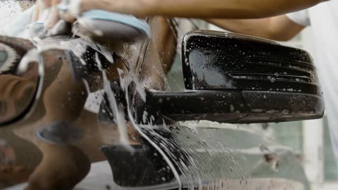 Dci 4k分辨率亚洲男人的手正在使用海绵和泡沫清洗黑色汽车和清洁脏灰尘。