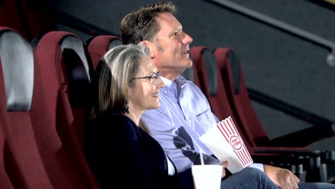 成熟的夫妇在剧院看电影，吃爆米花