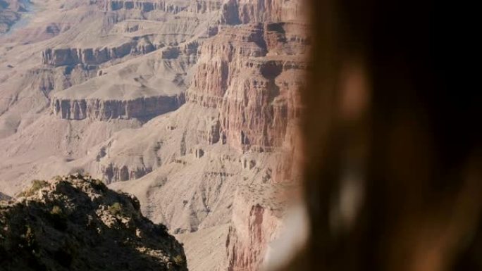 摄像机在幸福的女人的肩膀后面平移，享受着令人难以置信的大峡谷史诗般的沙漠山景。