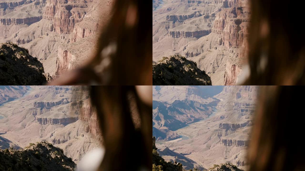 摄像机在幸福的女人的肩膀后面平移，享受着令人难以置信的大峡谷史诗般的沙漠山景。