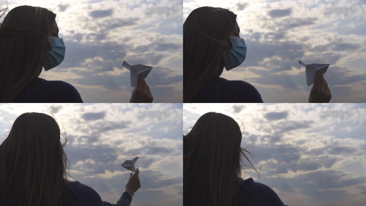 戴面具的漂亮女孩正在户外扔纸飞机。慢动作