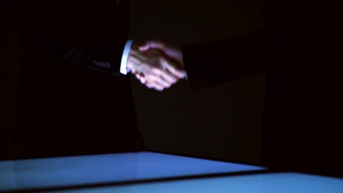 两个商人在大屏幕上握手。慢动作