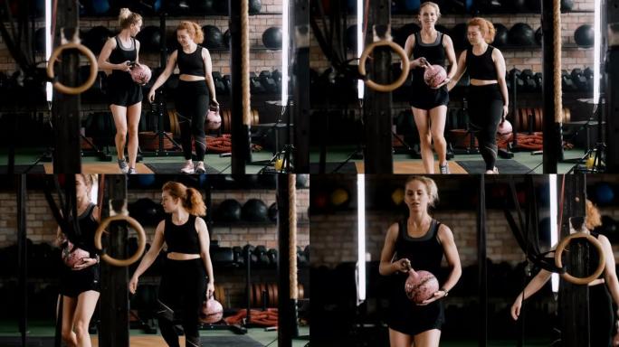 两名年轻漂亮的运动白人妇女带着壶铃举重运动员在健身房散步，随意慢动作。