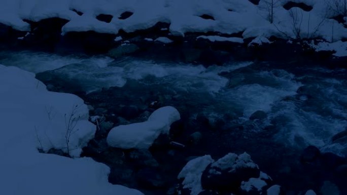 黄昏时雪中的山河流动河水冰雪融化