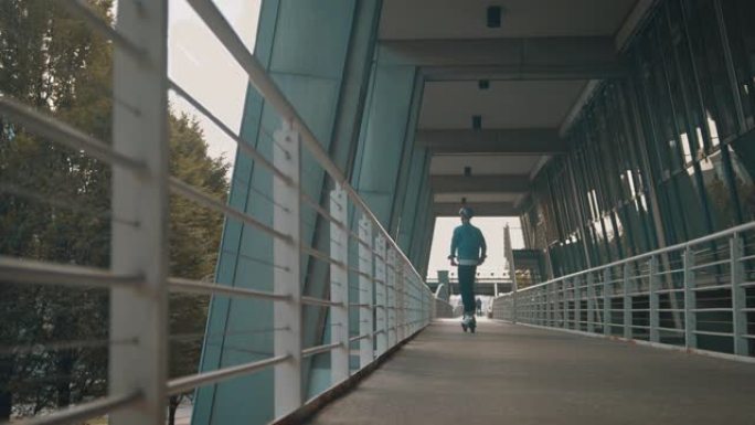 男子在桥上骑电动推动踏板车
