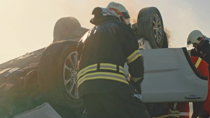 消防员救援队乘坐消防车抵达车祸现场。消防员抓住他们的设备，从消防车上准备消防水带和装备，急于营救受伤