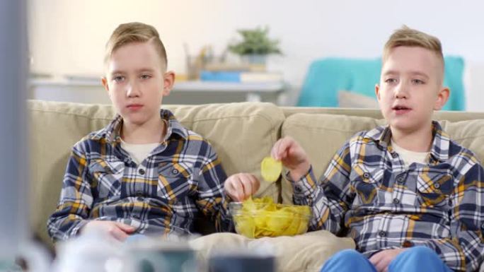 高加索双胞胎一起看电视和吃薯片