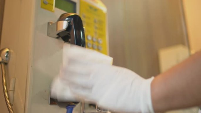 用手套清洁旧的公共电话亭表面，以便在购物中心或车站停止新型冠状病毒肺炎病毒