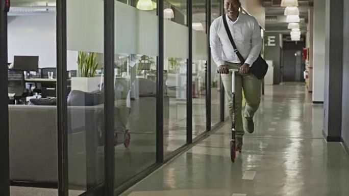 年轻的非洲商人在办公室里骑踏板车的慢动作视频