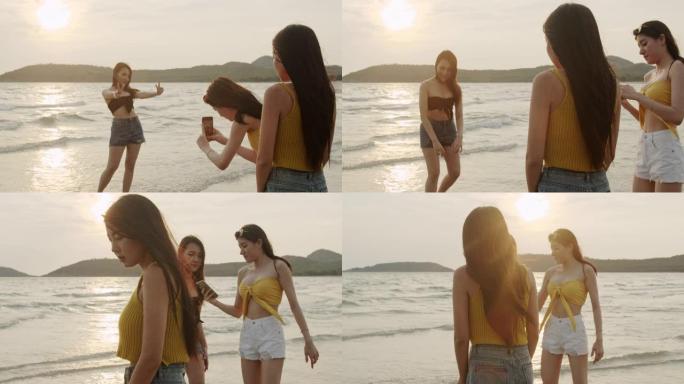 一群亚洲女性使用手机摄影并在海滩上玩耍，美丽的女性在傍晚日落时在海边的海滩上放松。女人在夏天的海滩上